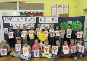 Dzieci z grupy Słoneczka pokazują wykonane przez siebie drzewka.