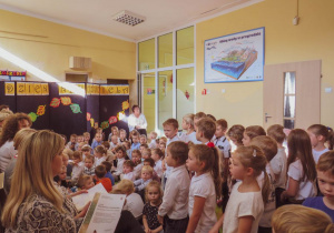 Dzieci na korytarzu śpiewają piosenki dla nauczycieli.
