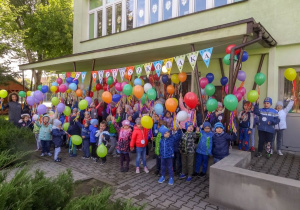 Dzieciaki pod przedszkolem z balonami.