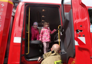 Dzieci oglądają wnętrze wozu strażackiego.