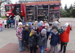 Dzieci stoją obok wozu strażackiego.