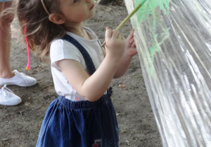 Dziewczynka maluje farbami na folii.