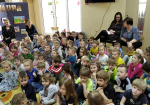 Dzieci słuchają opowieści o dinozaurach.