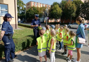 Policjant przypomina dzieciom zasady ruchu drogowego.