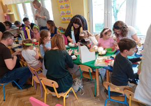 Dzieci z rodzicami dekorują jajka